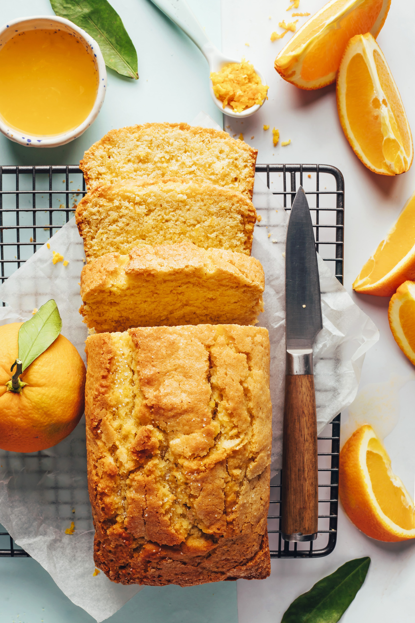 Partially sliced loaf of orange almond cake on a cooling rack