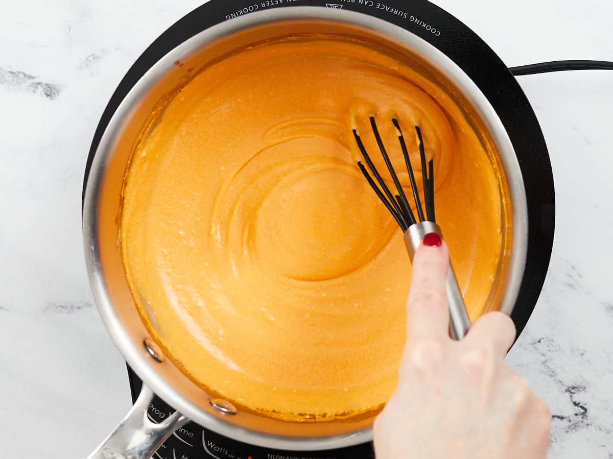 Smooth buffalo dip sauce in the pot with a whisk.