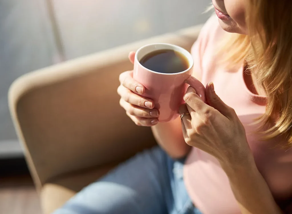 Girl Sitting On Sofa With Cup Of Coffee