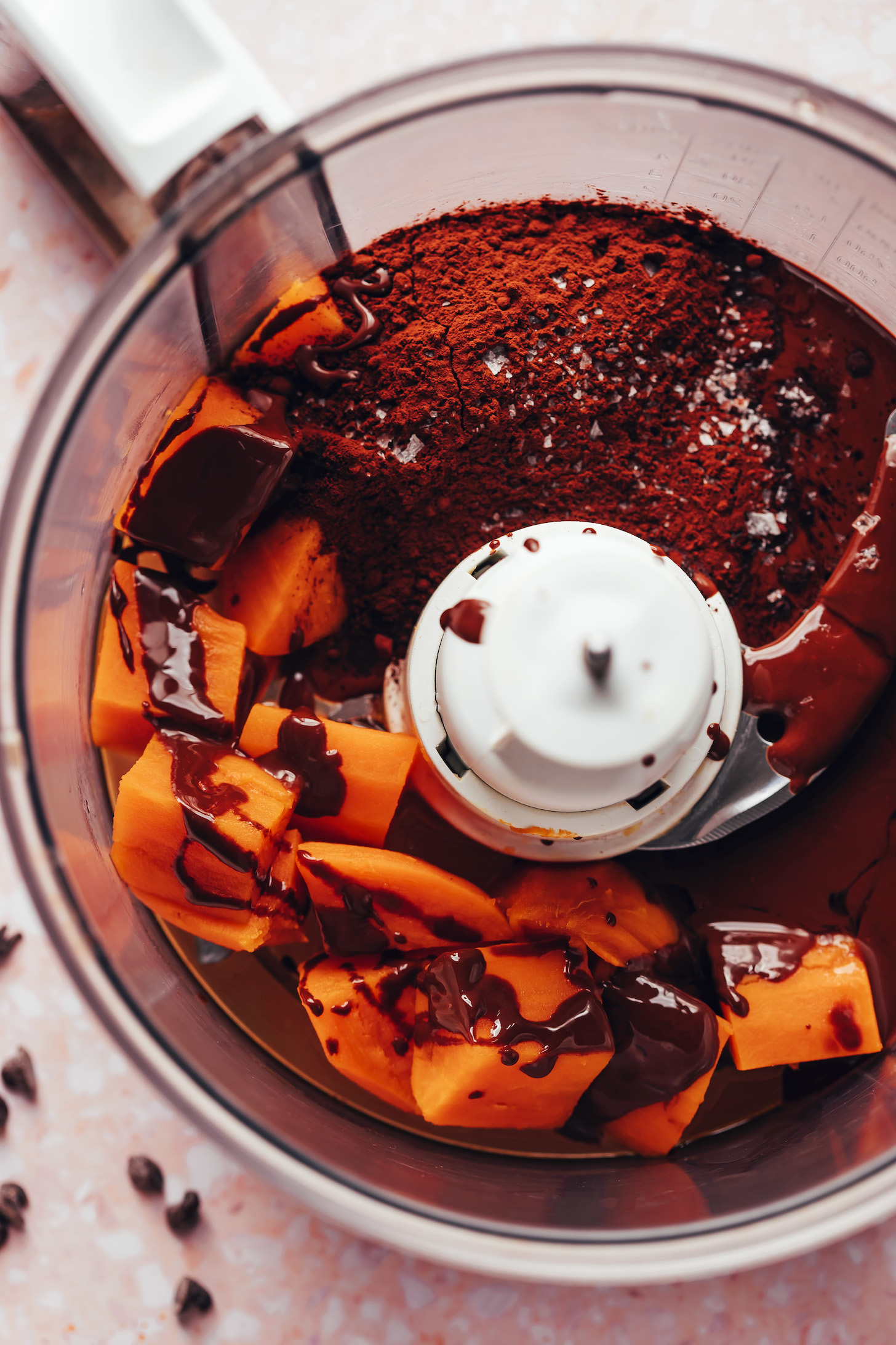Food processor with steamed sweet potato, melted dark chocolate, salt, and cocoa powder