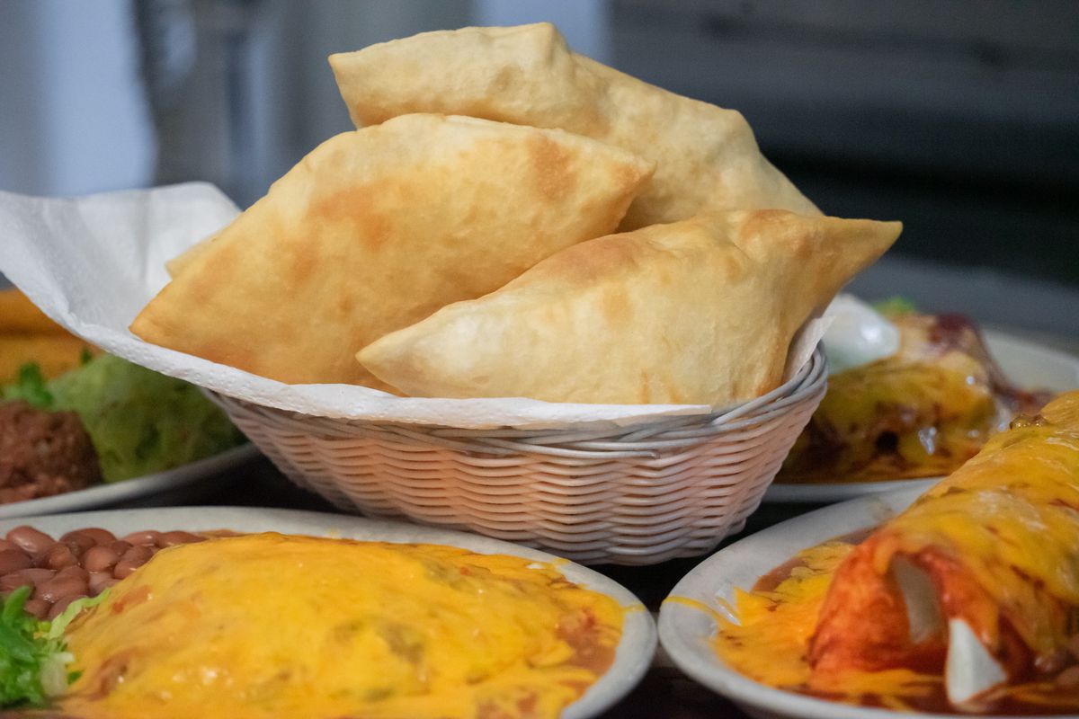 A basket of sopaipillas, alongside other New Mexican dishes.