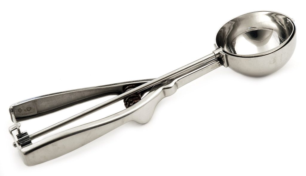 A metal ice scoop resting beside a bin of ice