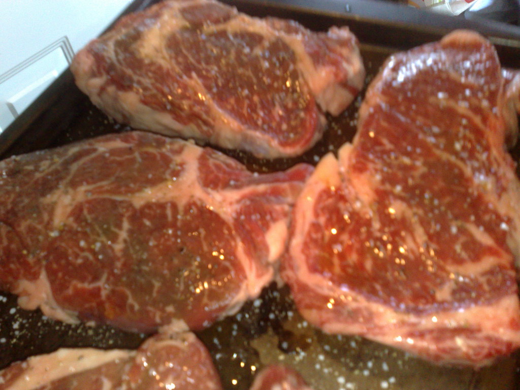 A raw bone-in ribeye steak on a cutting board