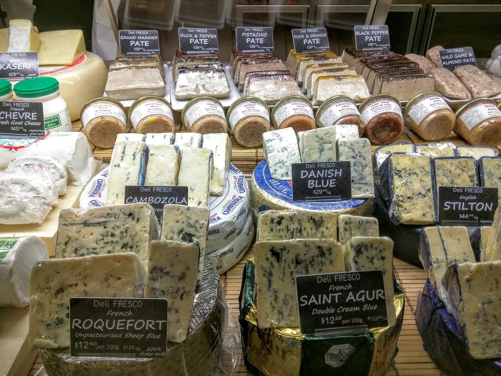 Wheels and wedges of cheese on a specialty cheese shop counter