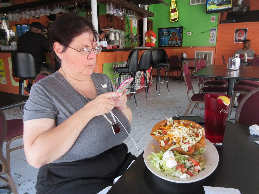 A smartphone lying on a restaurant table next to a menu