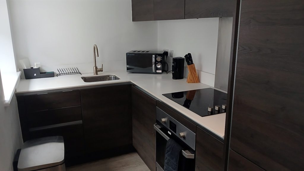 A stainless steel hand sink with soap and paper towel dispenser in a commercial kitchen