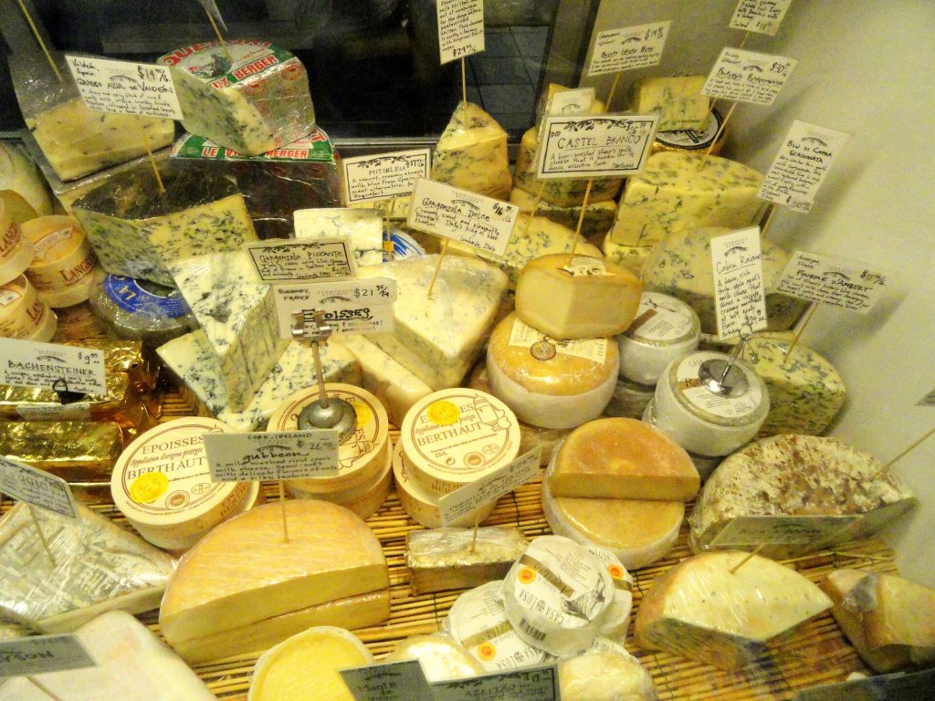 A deli counter displaying wheels and wedges of cheese