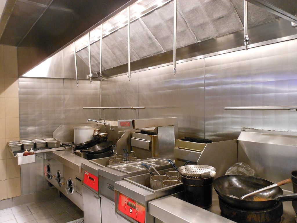 Commercial kitchen line under stainless exhaust hoods